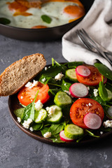 Fresh salad with spinach, radish, cucumbers and tomatoes.
