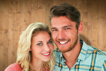 Attractive young couple smiling at camera against wooden planks