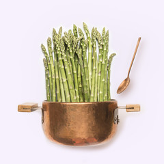 Asparagus in cooking pot with spoon on white background , front view.   Healthy vegetarian food and eating concept