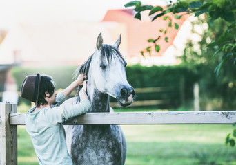 Young guy scratches his horse at summer outdoor nature