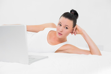 Obraz premium Thoughtful casual woman with laptop in bed