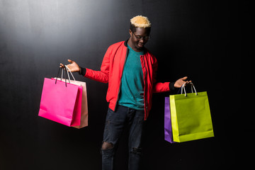 African American man with colorful paper bags isolated on black background