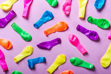 deflated balloons in different colors on a pink background