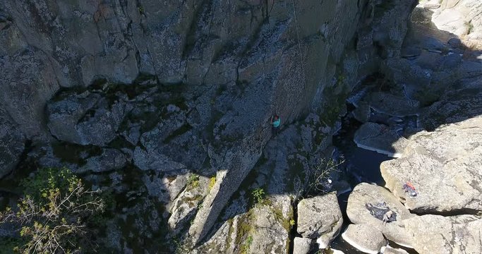 Two mountain climbers prepare an insurance rope at the bottom of a granite rock. Aerial view