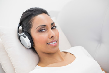 Happy attractive woman listening to music lying on couch