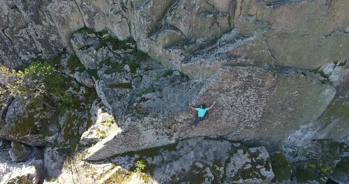 Climber is a man on a training climb on a rock among a granite canyon. Aerial view