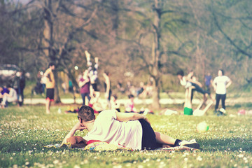 restful man at the park, He relaxing and other people doing physical activity on the background (soft vintage effect)