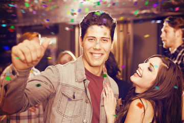 Stylish couple smiling and dancing together against flying colours