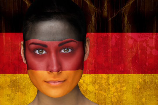 Composite image of beautiful football fan in face paint against germany flag in grunge effect