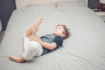 Little boy in pajama relaxing on the bed.
