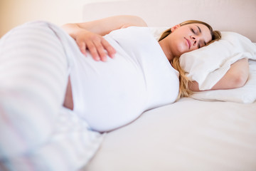 Obraz na płótnie Canvas Pregnant woman sleeping on bed