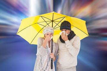 Couple in winter fashion sneezing under umbrella against blurry new york street