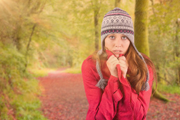 Cold redhead wearing coat and hat against peaceful autumn scene in forest