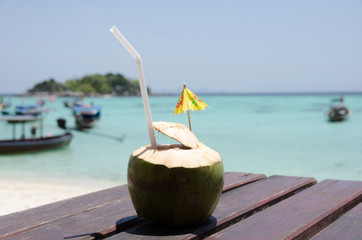 Drink coconut water naturally cool  on wooden table  with sea background.  Lipe © konjaunt