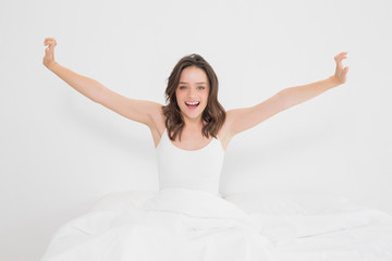 Smiling woman stretching her arms in bed