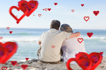Senior couple looking at the sea against love heart pattern