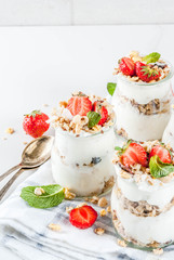 Obraz na płótnie Canvas Healthy summer breakfast idea, homemade layered parfe dessert in small jar with granola, yoghurt and strawberry, dark background copy space