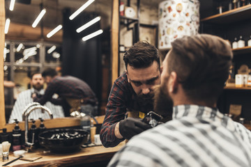 Fototapeta na wymiar Hipster young good looking man visiting barber shop. Trendy and stylish beard styling and cut.