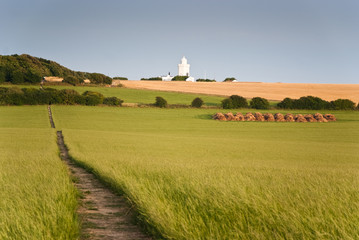 Landscape with white lighthouse over the hill