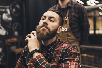 Hipster young good looking man visiting hairstylist in barber shop.