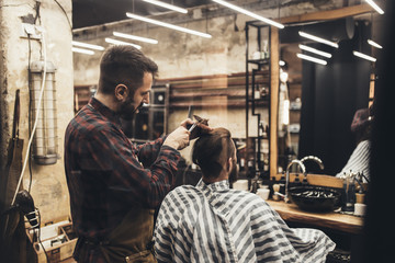 Fototapeta na wymiar Hipster young good looking man visiting hairstylist in barber shop.