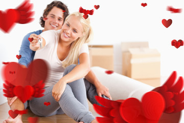 Woman sitting with her fiance giving keys against love heart pattern