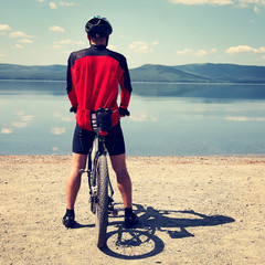 cyclist on the shore of a mountain lake