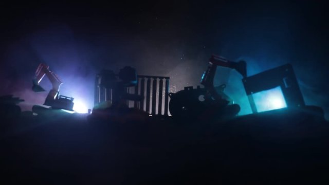 Construction site on a city street. A yellow digger excavator parked during the night on a construction site. Industrial concept table decoration on dark foggy toned background. Slider shot