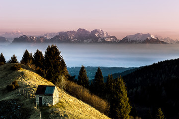 Sunrise on a solitary hut with in the background the dolomite peaks, Pian de le Femene, Veneto, Italy