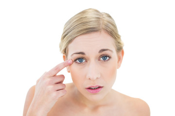 Naklejka premium Anxious young blonde woman pointing her eye with her finger