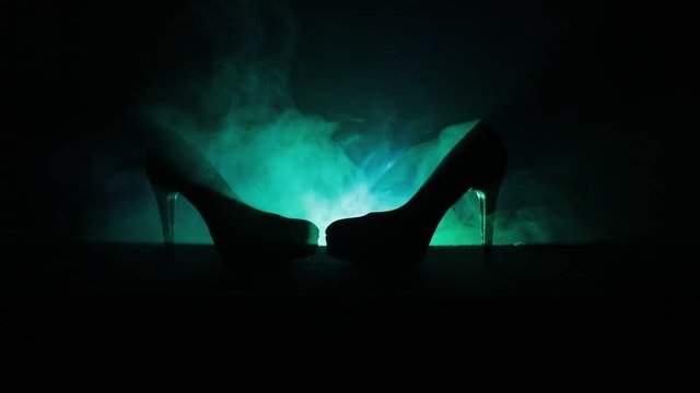 Black suede high heel women shoes on dark toned foggy background. Close up. Women power or women domination concept. Selective focus. Slider shot