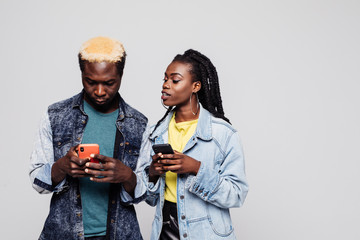 Portrait of a suspicious afro american couple with mobile phone isolated over white background. Afro american woman look at mans phone white he chating.
