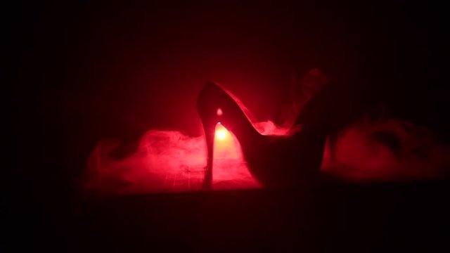 Black suede high heel women shoes on dark toned foggy background. Close up. Women power or women domination concept. Selective focus. Slider shot