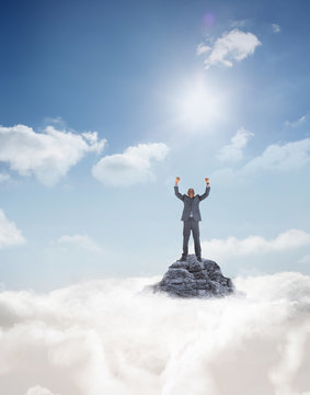 Happy Businessman Cheering Against Mountain Peak Through The Clouds