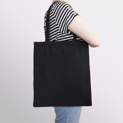 Dziewczyna trzyma czarną bawełnianą torbę ekologiczną, makieta projektu. - 202621467