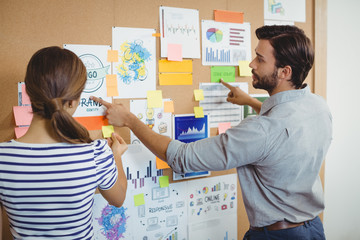 Male and female executives discussing over bulletin board - Powered by Adobe