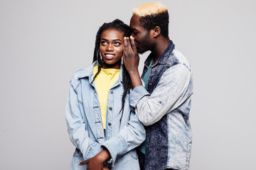 Portrait of a young african man dressed in summer clothes whispering a secret to his girlfriend isolated over white background