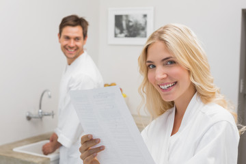 Obraz premium Smiling woman holding document with man in kitchen