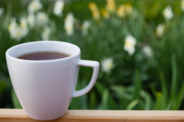 white cup of coffee on a background of flowers