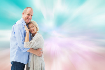 Happy mature couple hugging and smiling against digitally generated pink and blue girly design