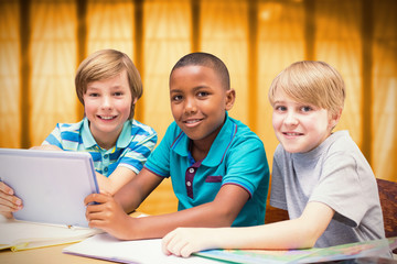 Cute pupils using tablet computer in library against window overlooking city