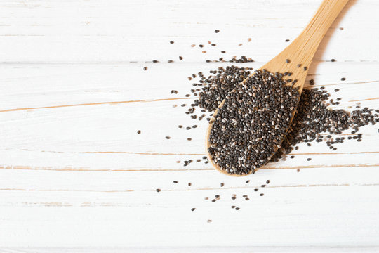 Raw chia seeds in wooden spoon on white background