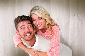 Handsome man giving piggy back to his girlfriend against wooden planks