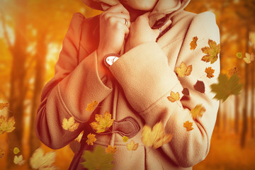 Attractive woman wearing a warm coat with hood raised against autumn scene