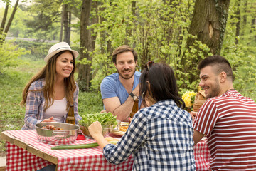 Two couples enjoying picnic day and eating barbecue together
