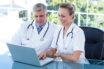 Smiling doctors working together on laptop