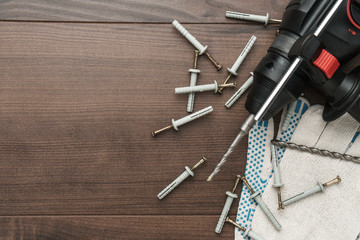 hammer drill and dowels on the wooden background with copy space