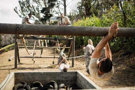 Young military soldiers practicing rope climbing during obstacle course