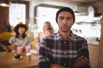 Portrait of confident man with arms crossed standing against female friends