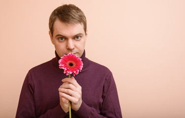 Young man hold gerbera flower in hand.